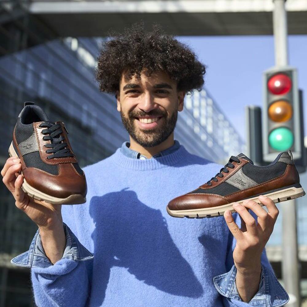 man holding a pair of rieker shoes