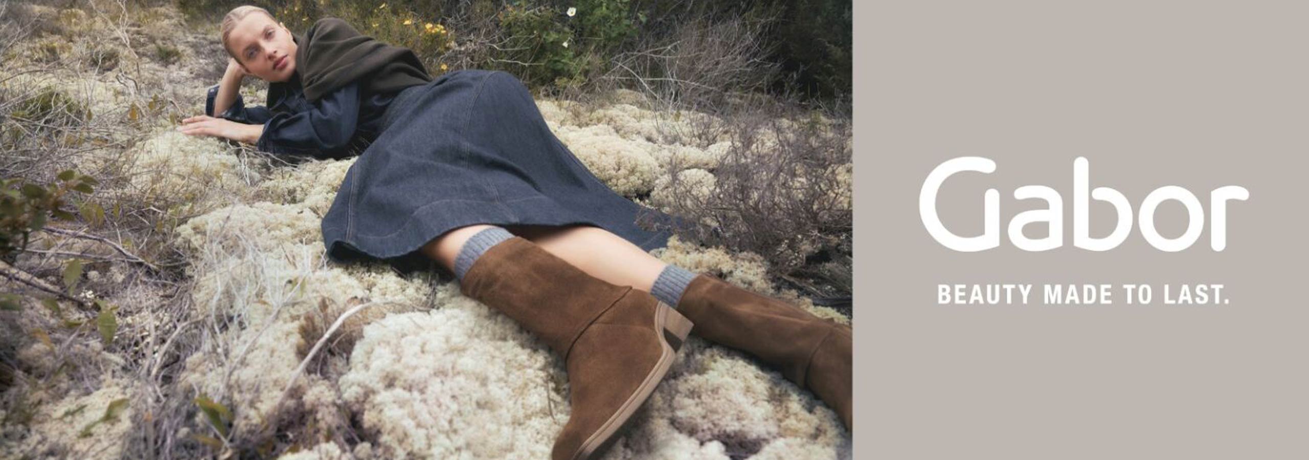 Person lying on a mossy ground wearing Gabor boots with brand logo and tagline.